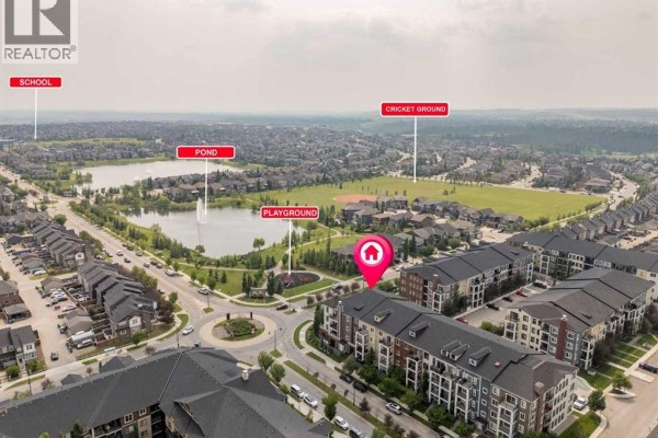 Aerial view showing the apartment building's location near a pond, playground, and cricket ground. - 4220, 215 Legacy Boulevard Se, Calgary