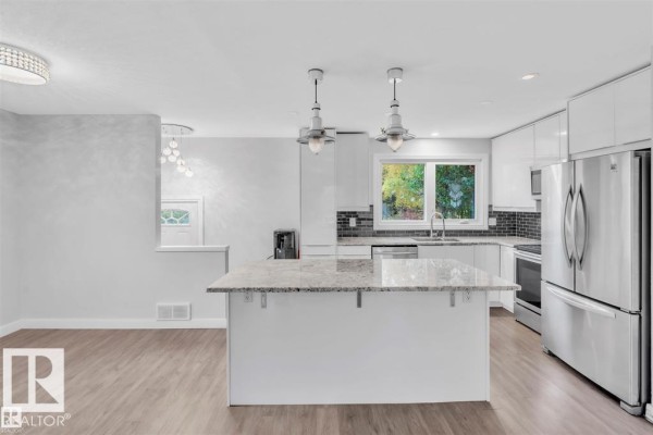 Kitchen with a large island, white cabinets, stainless steel appliances, and a view of the outdoors. - 42204b Twp Rd 624, Rural Bonnyville M D 