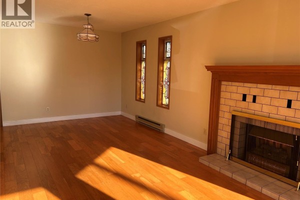 Living room with hardwood floors, a fireplace, and decorative stained glass windows. - 4225 Quadra St, Saanich