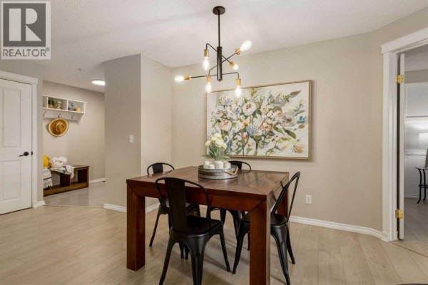 Dining area with a wooden table and black chairs, overlooking the entryway and into another room. - 4226, 10 Prestwick Bay Se, Calgary