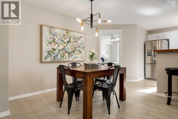 Dining area with a wooden table and chairs, view of a bedroom and stainless steel kitchen appliances. - 4226, 10 Prestwick Bay Se, Calgary