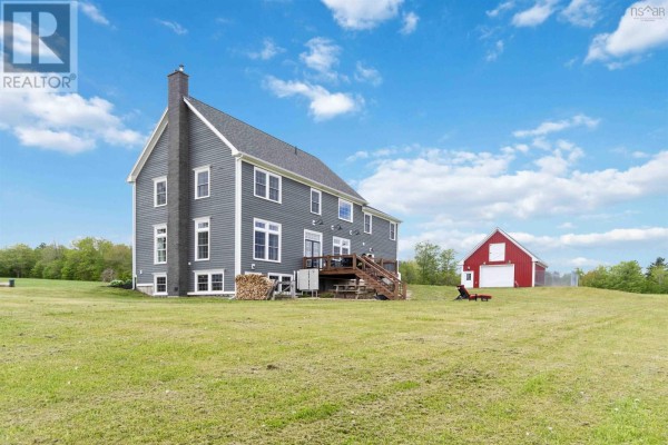 Rear exterior of a grey two-story house with a wooden deck and a detached red barn in the distance. - 423 Canaan Road, Nicholsville
