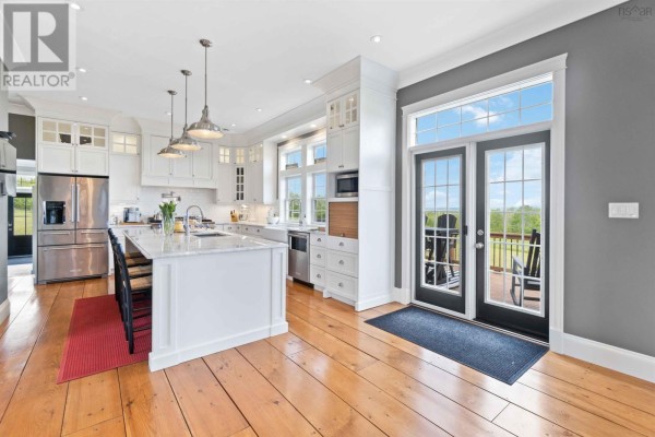 Bright white kitchen with a large island, stainless steel appliances, and double glass doors leading outside. - 423 Canaan Road, Nicholsville