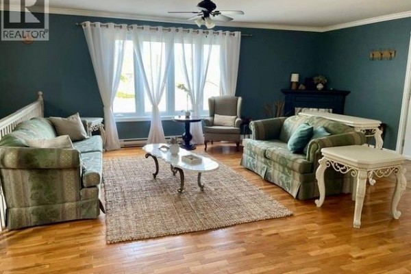 Living room with teal walls, checkered sofas, a fireplace, and hardwood floors. - 423 Darlington, Dalhousie