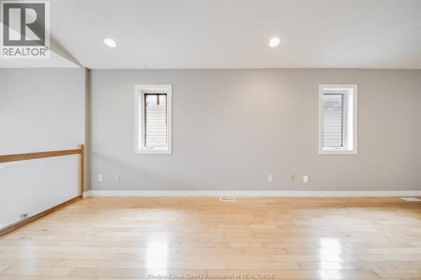 Spacious room with light wood floors and light grey walls, two small windows visible. - 4231 Whiskey Avenue, Windsor