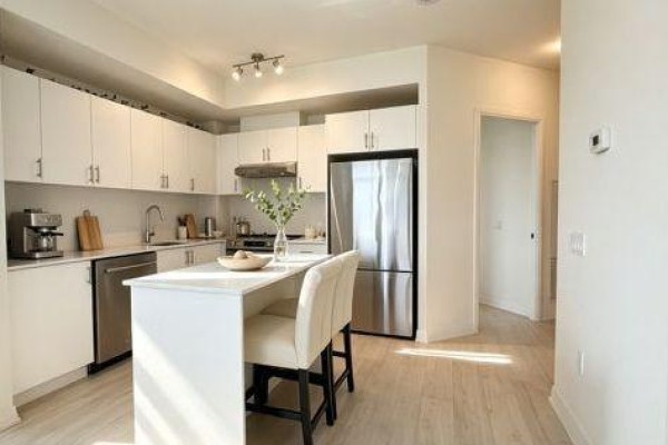 A large common area with wood floors, a kitchen island, and dining tables. - 424 - 9000 Jane Street, Vaughan