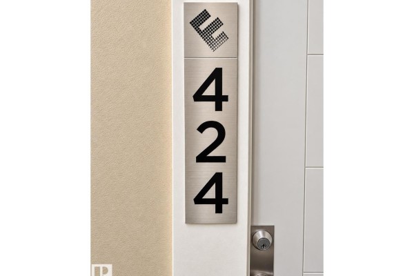 Close-up of the apartment door showing brushed metal signage with building logo and unit number 424. - #424 11074 Ellerslie Rd Sw, Edmonton