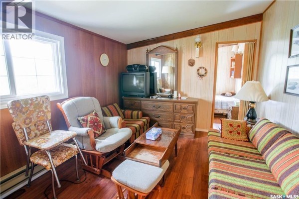 Covered deck with glass railing and snow on the ground overlooking a frozen body of water. - 424 Last Mountain Road, Last Mountain Lake