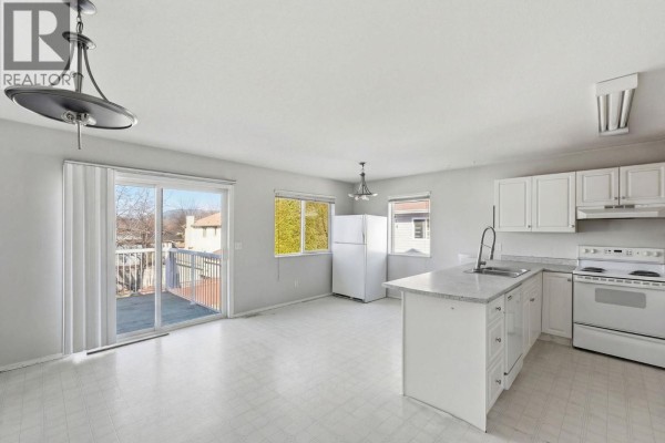 Bright kitchen with white cabinets, appliances, and access to deck - 424 Mclennan Mclennan Crescent, Kelowna