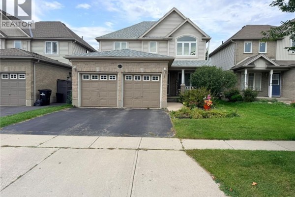 Exterior view of a beige-sided two-story house with a brick lower level and a double garage. - 424 Newport Drive, Cambridge