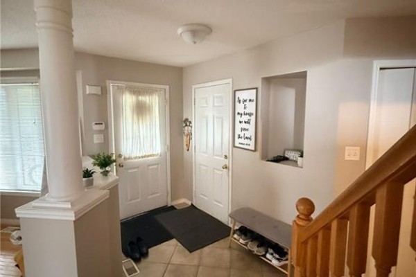 Interior entryway with tile flooring, two white doors, a column, and a staircase railing. - 424 Newport Drive, Cambridge