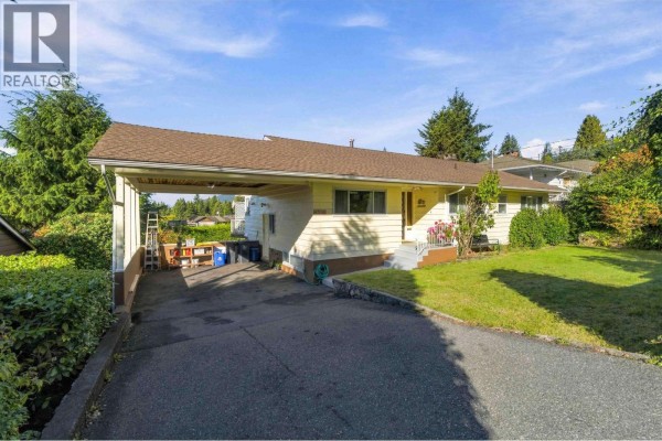 Exterior of a cream-colored house with a covered carport and driveway. - 4243 Delbrook Avenue, North Vancouver