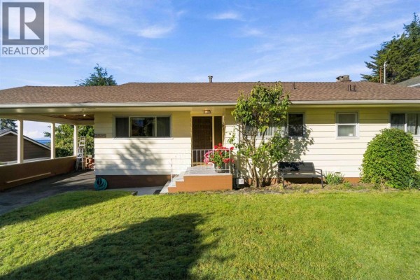 Front exterior of a cream-colored bungalow with a carport, lawn, and landscaping. - 4243 Delbrook Avenue, North Vancouver