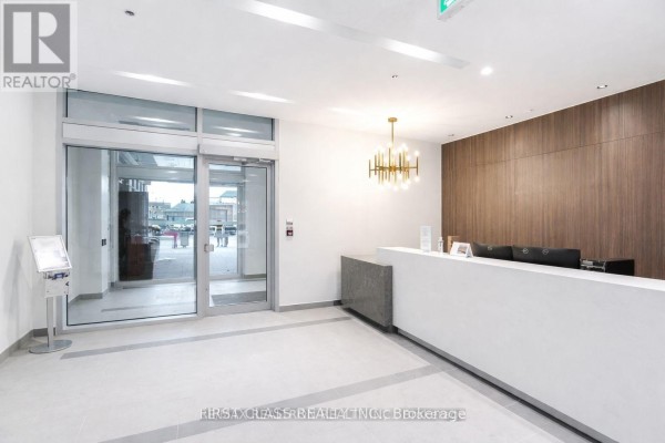 Building lobby with a white reception desk, modern chandelier, and wood accent wall. - 425 - 1787 St Clair Avenue W, Toronto