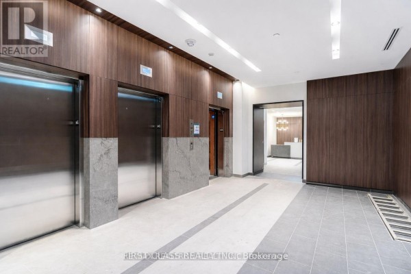 Building hallway with three elevators, wood paneled walls, and polished concrete floors. - 425 - 1787 St Clair Avenue W, Toronto