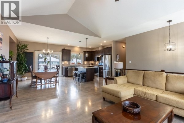 Open-concept living and dining area with modern kitchen, stainless steel appliances, and pendant lighting. - 425 Aralia Place, Logan Lake
