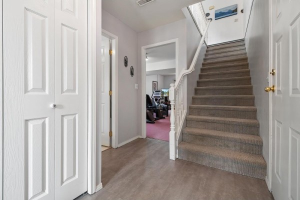 Interior hallway with a carpeted staircase leading upstairs, two closets, and a doorway to a room. - 425 Hadway Drive, Harrison Hot Springs, Harrison Hot Springs
