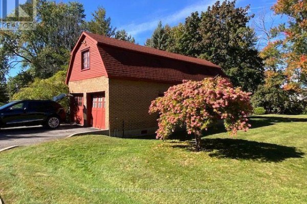 Brick detached garage with two red doors and a gambrel roof, next to a driveway. - 425 Second St. E Street E, Cornwall