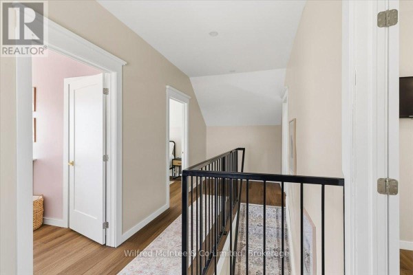 Modern hallway with hardwood floors, black metal railing, white doors - 425 Yonge Street S, Brockton