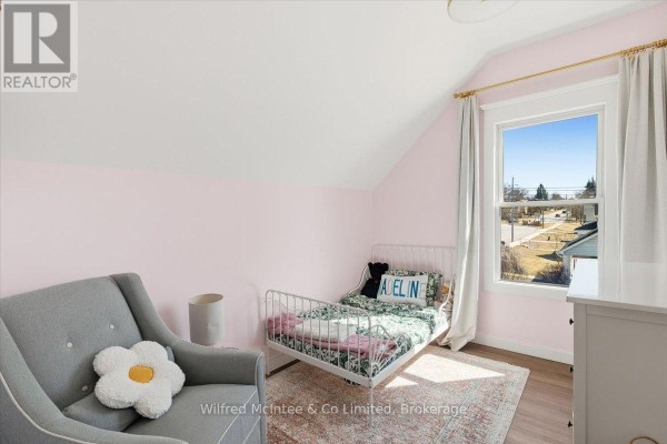 Renovated bedroom with sloped ceiling, window, and bed - 425 Yonge Street S, Brockton