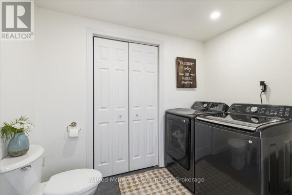 Modern laundry room with toilet, washer, dryer, and bi-fold doors - 425 Yonge Street S, Brockton