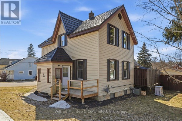 House exterior with metal roof, tan siding, black shutters, front porch - 425 Yonge Street S, Brockton