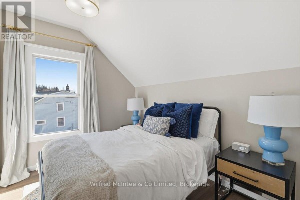 Modern bedroom with window, bed, two nightstands, and sloped ceiling - 425 Yonge Street S, Brockton