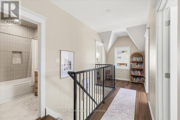 Renovated hallway with hardwood floors, black railing, and tiled bathroom - 425 Yonge Street S, Brockton