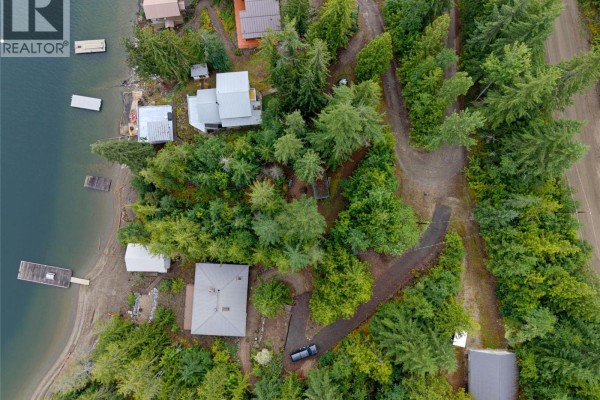 Aerial view of several lakeside properties surrounded by dense evergreen trees and a dirt road. - 4255 Justin Road, Eagle Bay