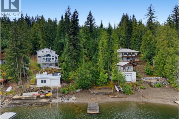 Lakefront view of multiple houses on a forested hillside, with docks and boat lifts visible. - 4255 Justin Road, Eagle Bay