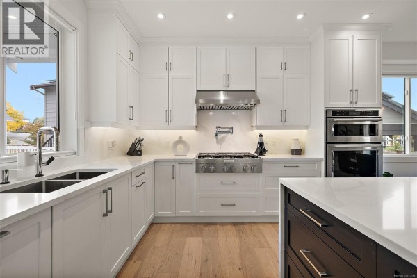 White kitchen cabinetry, marble countertops, and stainless steel appliances including a gas range. - 4257 Pullet Pl, Saanich