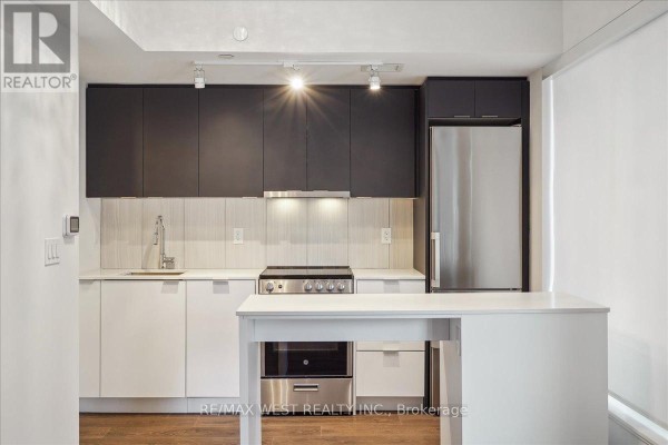 Close-up of a modern kitchen with dark and white cabinets and stainless steel appliances. - 426 - 8 Tippett Road, Toronto