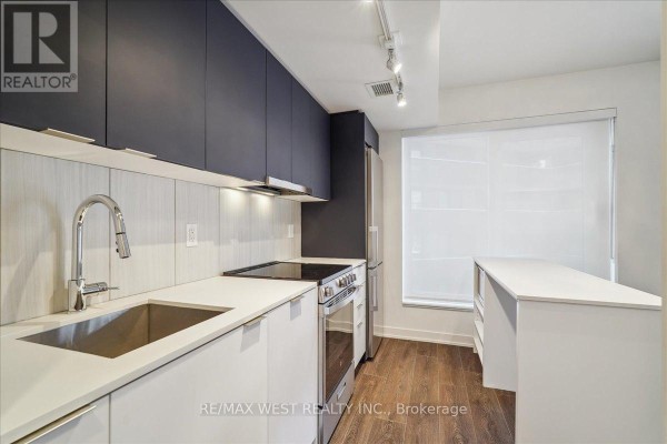 Kitchen counter with sink, faucet, stove, and white island with a view of window. - 426 - 8 Tippett Road, Toronto