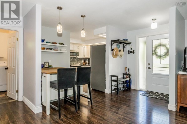Dining room with a wooden table, chairs, buffet, and view into the kitchen and living area. - 426 Granville Street E, Bridgetown
