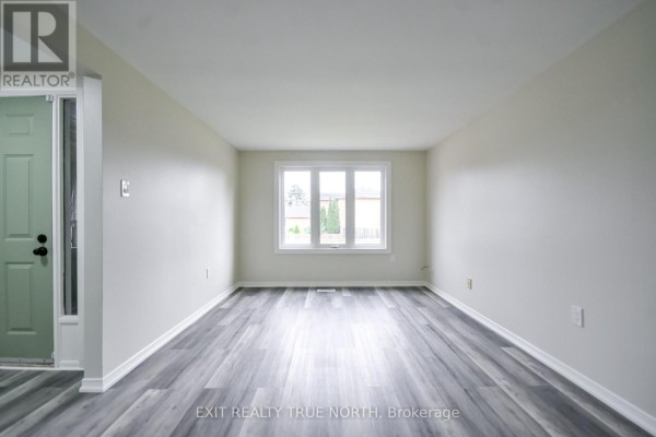 View of the entryway and a large living room with grey wood-look flooring. - 426 Sunnidale Road, Barrie
