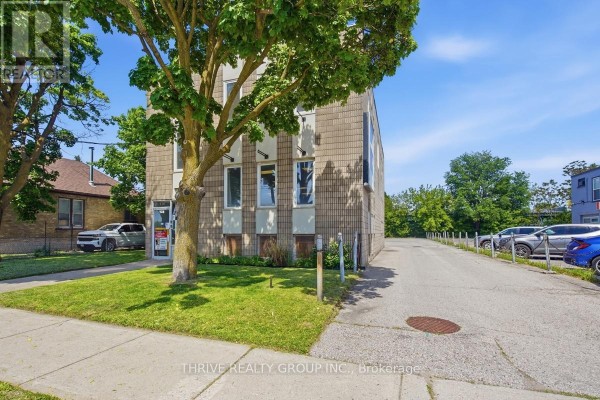 Side view of commercial building with parking lot and green trees. - 426 Third Street, London East