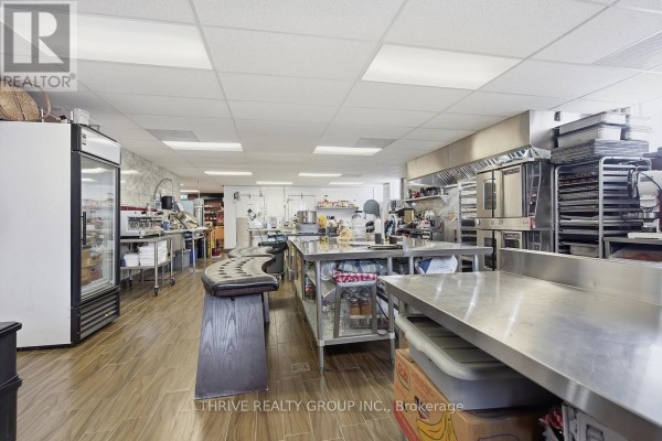 Commercial kitchen with stainless steel counters, ovens, refrigerators, and tiled floor. - 426 Third Street, London East