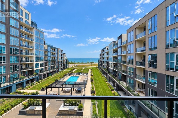 View from apartment balcony overlooking courtyard with pool, seating, and lake in distance. - 427 - 16 Concord Place, Grimsby