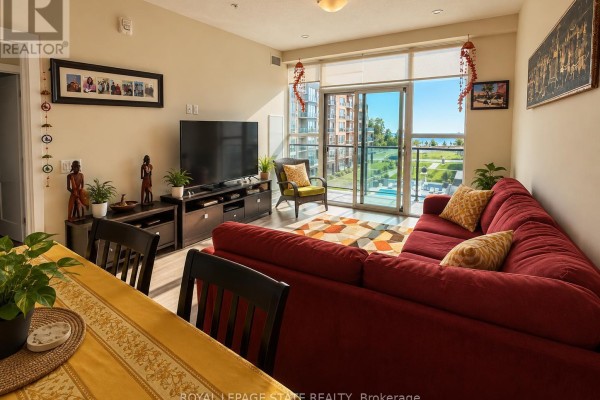 Living room with red sectional sofa, TV, patterned rug, and sliding glass doors. - 427 - 16 Concord Place, Grimsby