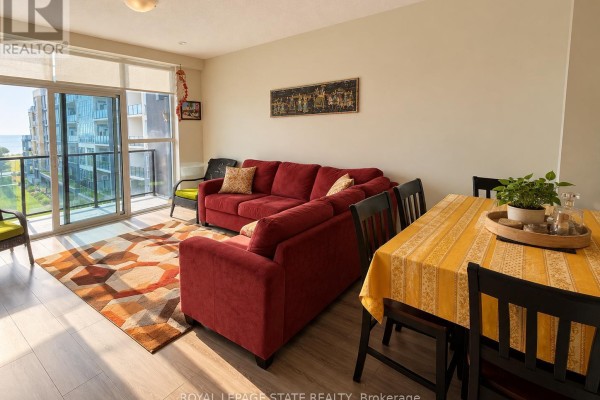 Living and dining area with red sectional sofa, dining table with yellow tablecloth, and floor-to-ceiling windows. - 427 - 16 Concord Place, Grimsby
