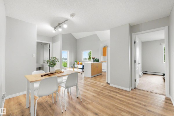 View from dining area to living room, kitchen, and a hallway leading to a bedroom. - #427 3425 19 St Nw, Edmonton