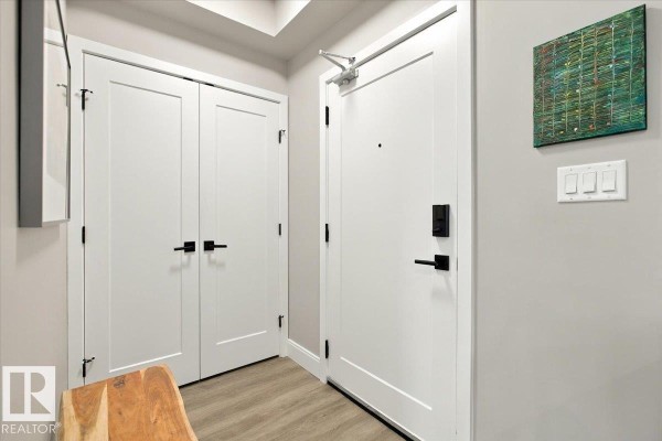 Apartment entrance with two white doors, a gray wall, and a piece of abstract art. - #427 7463 May Cm Nw, Edmonton