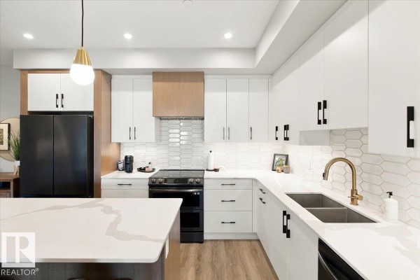 Contemporary kitchen with white cabinets, black appliances including a French door refrigerator, and a large island. - #427 7463 May Cm Nw, Edmonton
