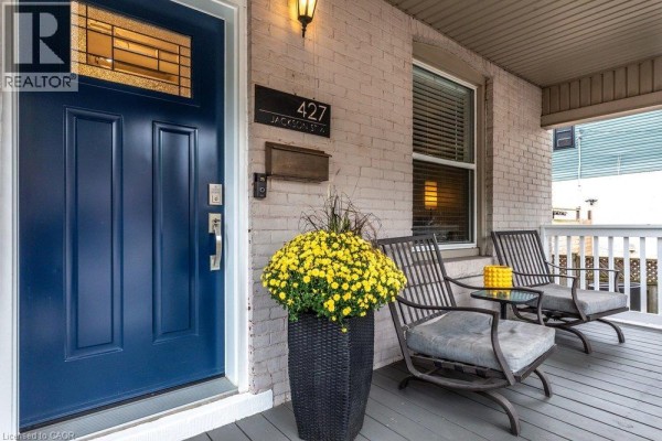 Detail of the navy blue front door, house number, mailbox, and two chairs on the porch. - 427 Jackson Street W, Hamilton