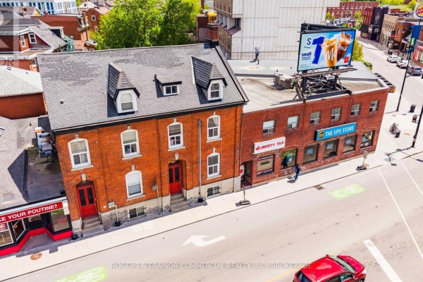 Aerial view of brick buildings at a street intersection with commercial signage and traffic. - 427 Princess St. & 177-181 Division Street, Kingston