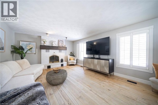 Living room with a large TV, sectional sofa, and white brick fireplace. - 428 Charlotteville Road 1, St  Williams