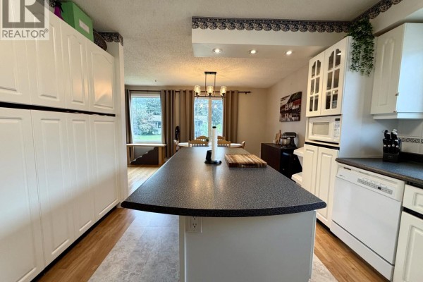 Kitchen with a large island, white cabinets, and view of dining area and windows. - 4280 First Avenue, Smithers