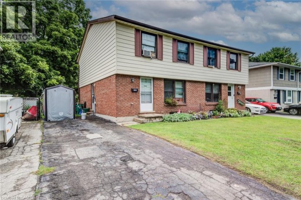 Side view of a split-level duplex with brick and siding, driveway, and parked cars. - 428b Dunvegan Drive, Waterloo