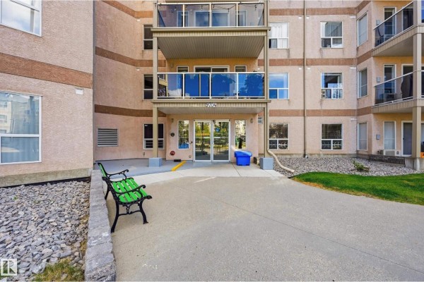 Building entrance with blue glass balconies and green bench outside. - #429 9704 174 St Nw, Edmonton