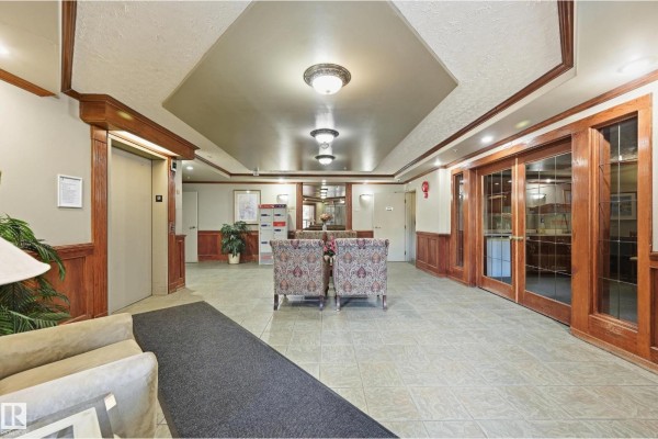 Apartment building lobby with elevator, mailboxes, and seating area. - #429 9704 174 St Nw, Edmonton